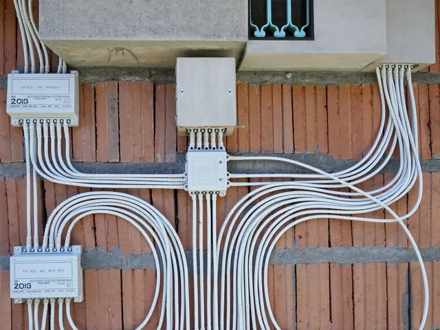 New electrical wiring in white conduits installed along a brick wall in Bali